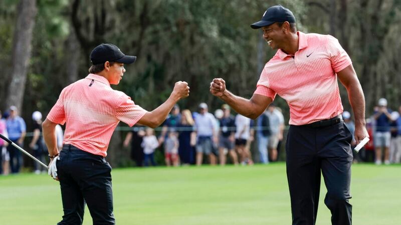Tiger Woods, right, fist bumps his son Charlie Woods, left, after finishing the 9th hole...