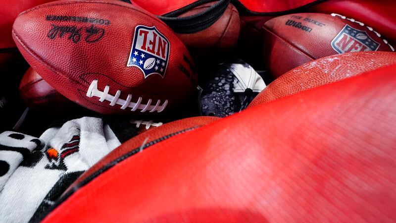 NFL footballs lie on the turf before the first half of an NFL football game between the...